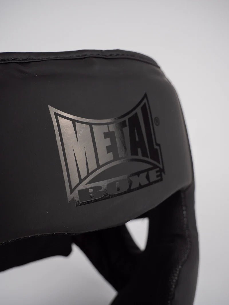 Detailní záběr loga Metal Boxe vytištěného na skořepině černé helmy Full Face "Black Light".