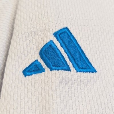Detail tří pruhů Adidas a modrého loga italské verze na rameni judogi