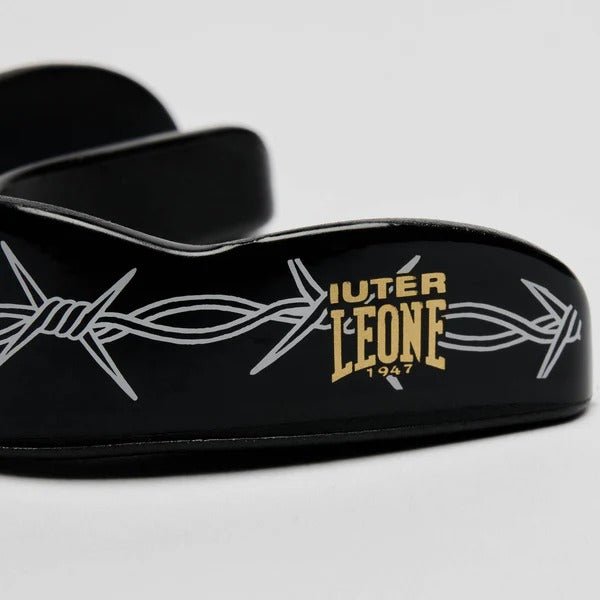 Nahaufnahme des goldenen LEONE x IUTER-Logos und der Barbed Wire-Grafik