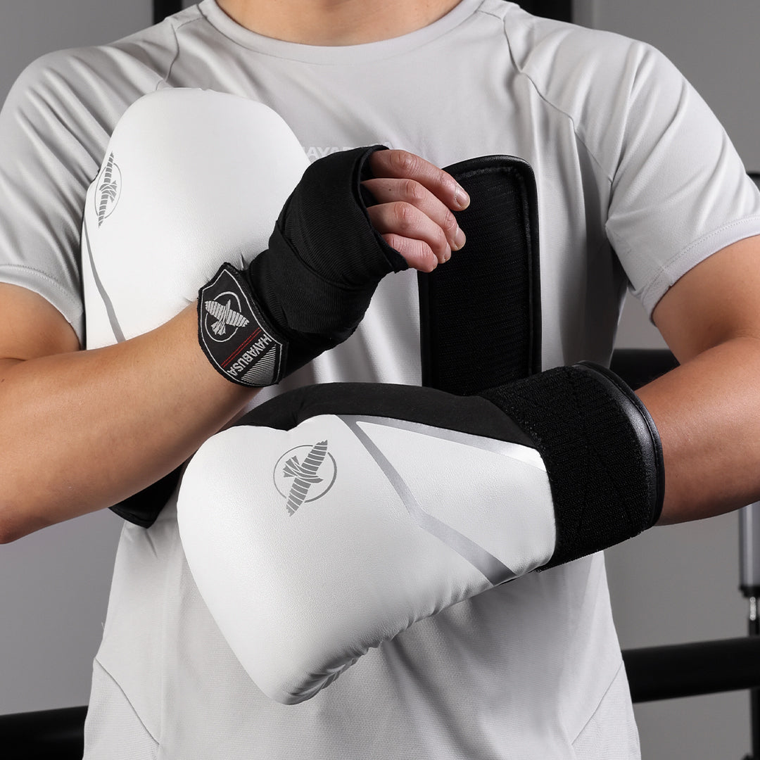 Atleta che indossa i guantoni da boxe bianchi Hayabusa E1 in posizione di guardia