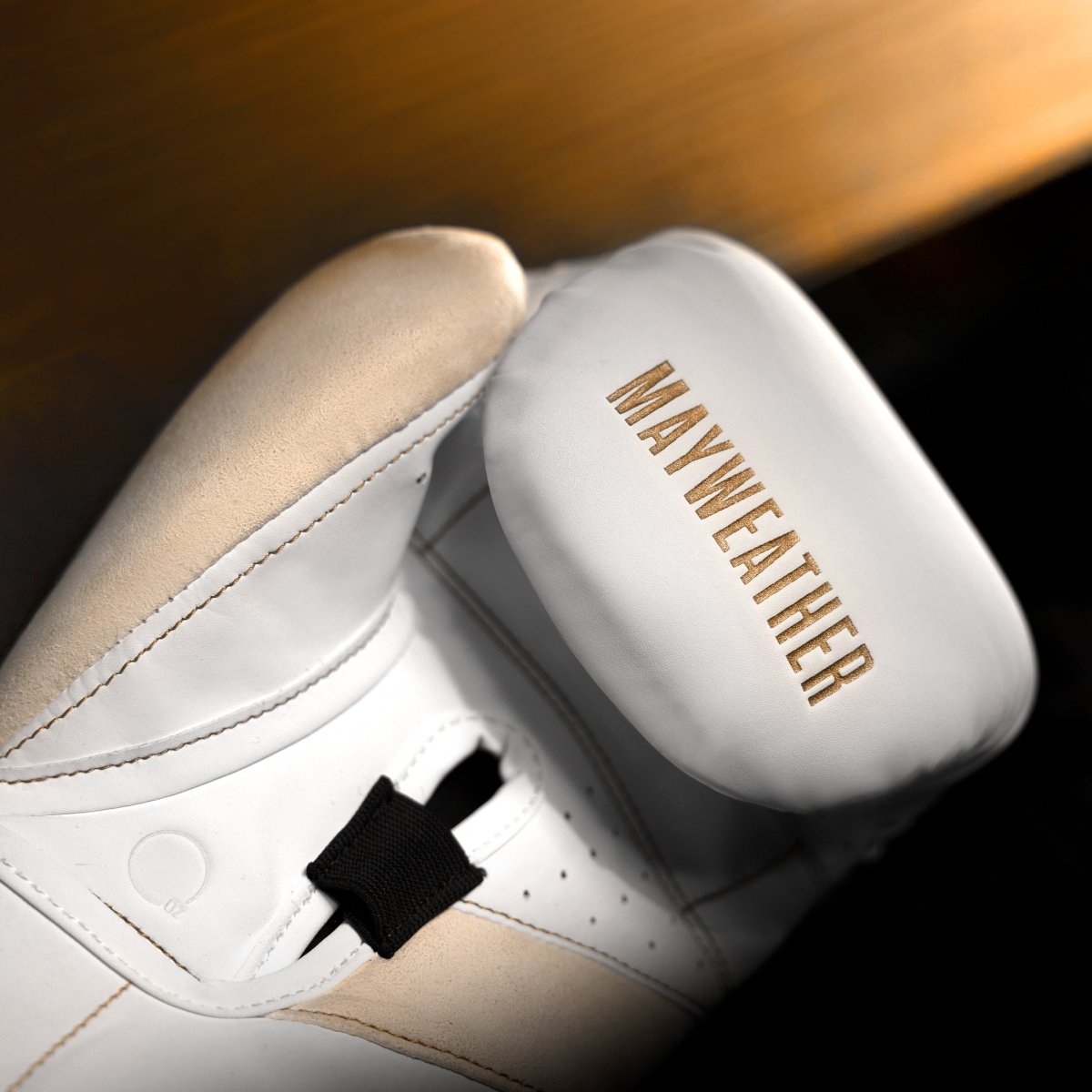 Detalhe do acolchoamento interno e da barra angular das luvas Mayweather Champ em ouro branco