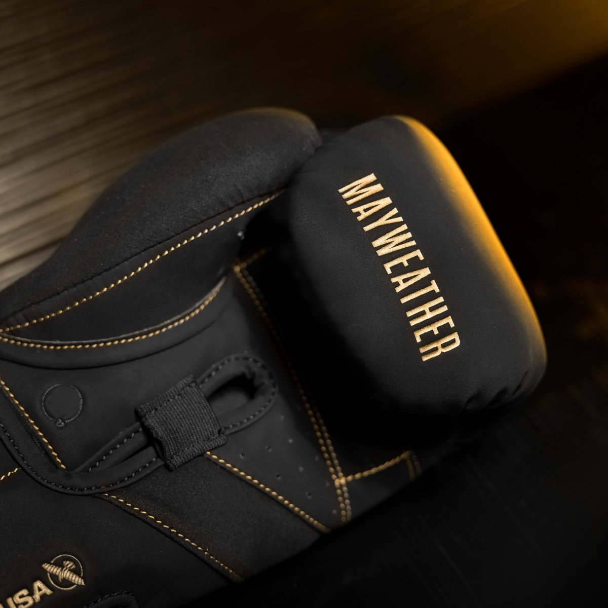 Detalhe do acolchoamento interno e da barra angular das luvas Mayweather Champ em ouro preto