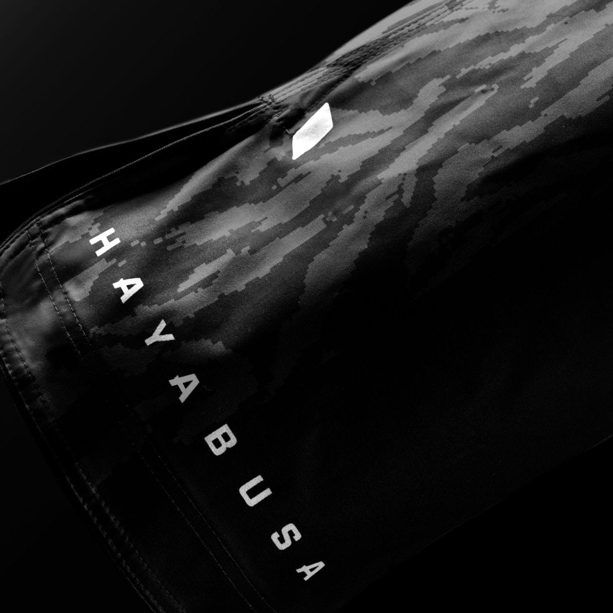 Detail close-up tulisan merek Hayabusa di bagian kaki celana pendek Apex 3/4 berwarna hitam