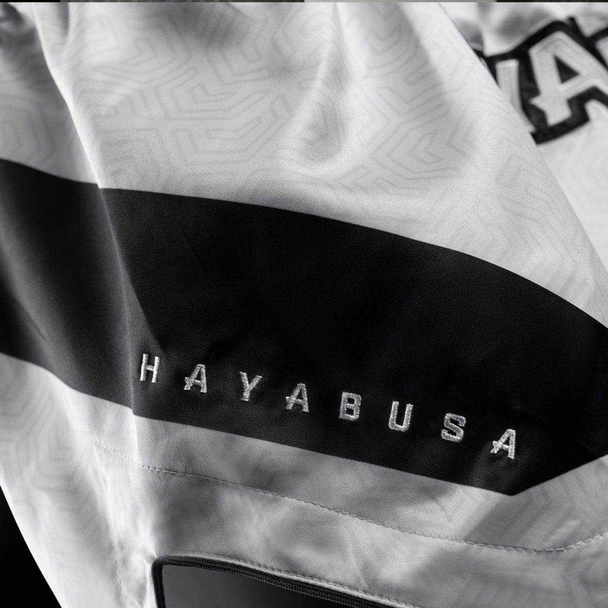 Detail kain teknis dan logo pada celana pendek Hayabusa Core berwarna putih